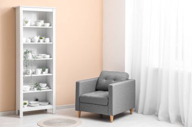 Bulaşıkları ve bej duvarın yanındaki koltuğu olan modern raf ünitesi.