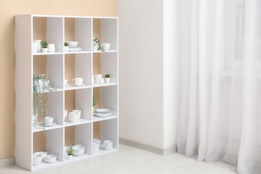 Mutfaktaki ışık perdesinin yanında temiz bulaşık takımı olan modern raf ünitesi