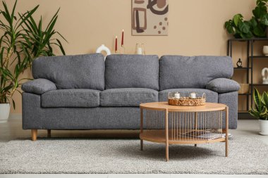 Hasır tepside evdeki kanepenin yanındaki masada güzel mumlar var.