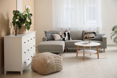 Çekmeceler, rahat kanepe ve oturma odasındaki bej duvarın yanındaki kahve masası.