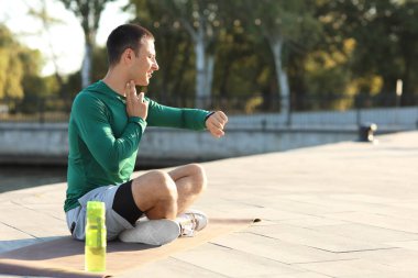 Sportif genç adam antrenmandan sonra nabzını kontrol ediyor.