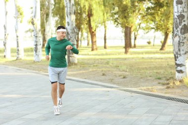 Dışarıda koşarken saatine bakan genç bir adam.