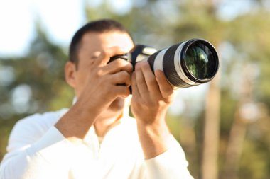 Park yerinde modern kameralı bir erkek fotoğrafçı.