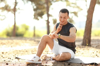 Sportif genç adam antrenmandan sonra nabzını kontrol ediyor.