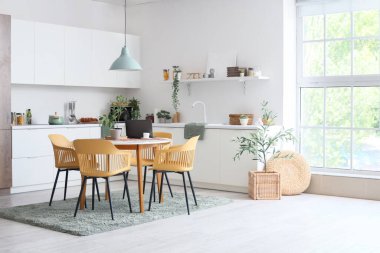 Masası, sandalyeleri ve beyaz tezgahı olan hafif yemek odasının içinde.