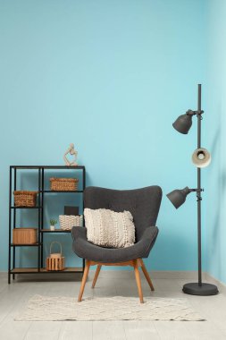 Yer lambası, koltuk ve raf odası mavi duvarın yanında.