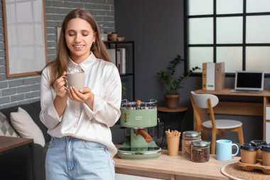 Ofisinde bir fincan kahve olan genç bir iş kadını.