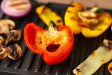 Arka planda lezzetli sebzeler olan modern elektrikli ızgara, yakın plan.