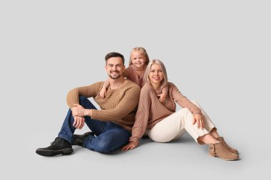 Kışın kızı olan mutlu çift gri arka planda oturuyor.