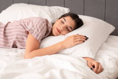 Genç ve güzel bir kadın sabahları yatakta uyuyor.