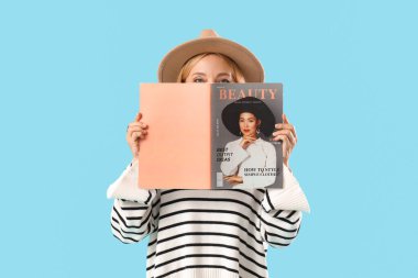 Mavi arka planda dergisi olan güzel olgun bir kadın.