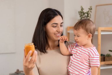 Mutlu bir anne, tatlı bir bebek ve evde bir kavanoz lezzetli yemek.