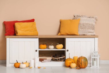 Yastık, balkabağı ve fener bej duvarın yanında.