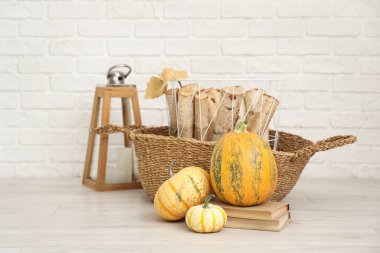 Şömine için odun, beyaz tuğla duvarın yanında yerde sonbahar süslemeleri var.