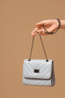 Bej arka planda şık mavi çantalı kadın eli, yakın plan.