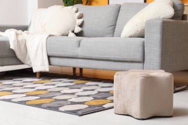 Gri kanepe, yumuşak puf ve halısı olan şık bir oturma odası.