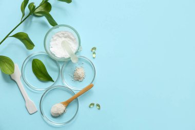 Mavi arka planda doğal kozmetik ürünleri hazırlamak için bitkiler ve malzemelerle dolu petri kapları