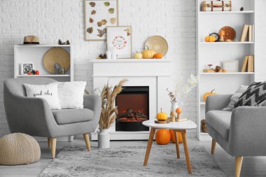 Şöminesi, sehpası, kanepesi ve balkabağı olan şık bir oturma odası. Sonbahar konsepti