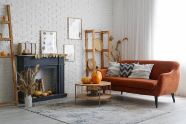 Şömineli, sehpalı, kanepeli ve balkabaklı şık bir oturma odası. Sonbahar konsepti