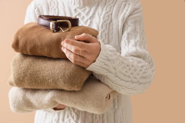 Şık sonbahar kıyafetleri ve bej arka planda kemeri olan kadın, yakın plan.