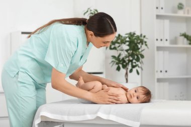 Sevimli küçük bebek klinikteki koltukta mutlu bir terapistten masaj yaptırıyor.