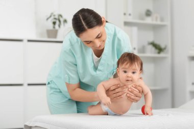 Sevimli küçük bebek klinikteki koltukta mutlu bir terapistin topuyla masaj yaptırıyor.