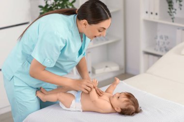 Sevimli küçük bebek klinikteki koltukta mutlu bir terapistten masaj yaptırıyor.