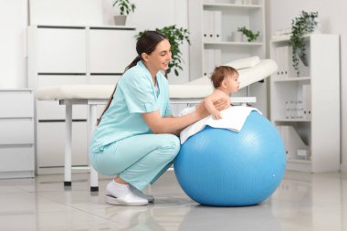 Klinikteki mutlu profesyonel terapistten Fitball 'a masaj yaptıran şirin küçük bebek.