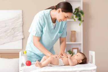 Sevimli küçük bebek klinikteki koltukta mutlu bir terapistten karın masajı yaptırıyor.