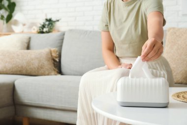 Kadın evdeki sehpanın üstündeki seramik tutucudan doku alıyor.