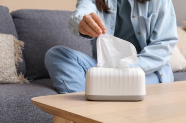 Oturma odasındaki sehpanın üzerindeki seramik tutucudan doku alan kadın.