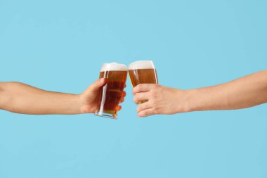 Mavi arka planda soğuk bira bardakları tokuşturan erkek elleri. Ekim Festivali Kutlaması