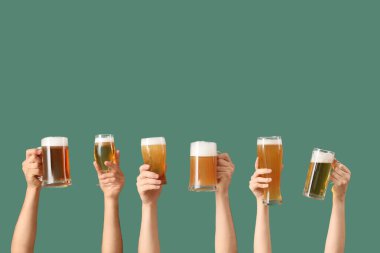 Yeşil arka planda bardaklar ve kupalar dolusu soğuk bira olan bir sürü el. Ekim Festivali Kutlaması