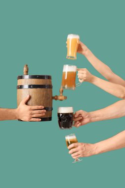 Fıçılı erkek eller, yeşil arka planda bardaklar ve kupalar dolusu soğuk bira. Ekim Festivali Kutlaması