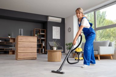 Kadın temizlikçi. Ofiste yerleri süpürüyor.