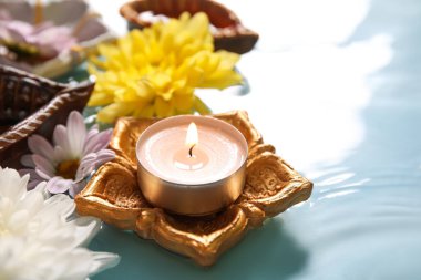 Güzel çiçekli Diya lambaları ve mavi arka planda suda yanan mumlar. Divaly kutlaması