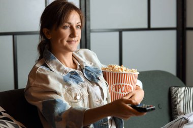 Akşam evde patlamış mısırlı genç bir kadın film izliyor.