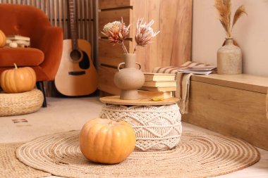 Kahve masası, balkabakları, akustik gitar ve sonbaharda oturma odasının iç kısımlarında çiçek vazosu.