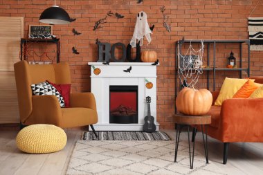 Cadılar Bayramı için dekore edilmiş oturma odasının içinde şömine, kanepe ve koltuk var.