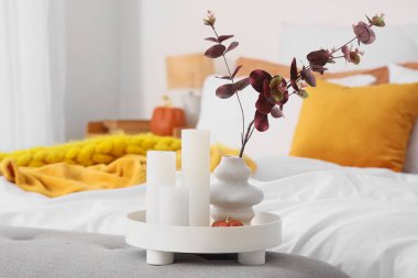 Okaliptüs dallı vazo, mum ve balkabağı yatak odasında, yakın plan.