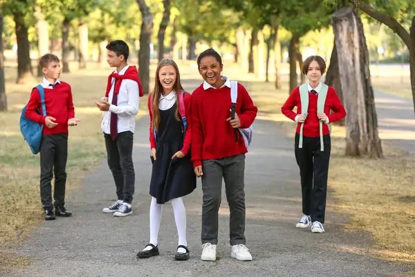 Bir grup mutlu öğrenci açık havada okula gidiyor.