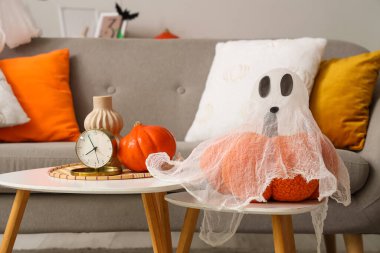 Cadılar Bayramı balkabaklı hayalet ve oturma odasındaki masalarda çalar saat, yakın plan.