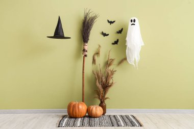 Cadılar Bayramı balkabaklı cadı süpürgesi, otlu otlar ve yeşil duvarın yanındaki oda hayaleti.