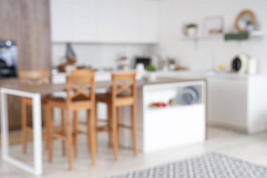 Beyaz tezgahlı, masa ve raflı modern mutfağın bulanık görüntüsü