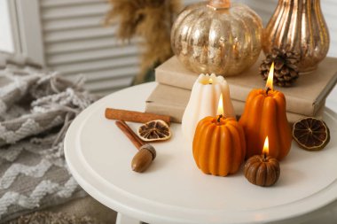 Sonbahar yapraklı balkabağı şeklinde mumlar yakmak ve evdeki tabure üzerine kitaplar, kapanış.