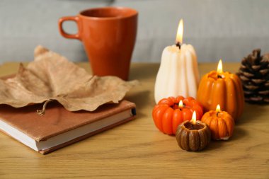 Balkabağı şeklinde mumlar yakmak, çay fincanı ve kitap evdeki sehpanın üzerinde, yakın çekim.