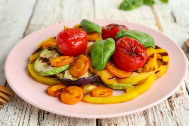 Izgara sebzeli tabak ve beyaz ahşap masada fesleğen.