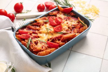 Beyaz fayanslı domates soslu ve peynirli makarna kabı.