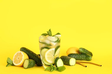 Bir bardak salatalıklı limonata ve sarı arka planda nane şekeri.