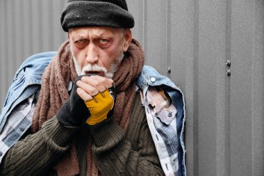 Sokakta çitin yanında donmuş evsiz adam, yakın plan.